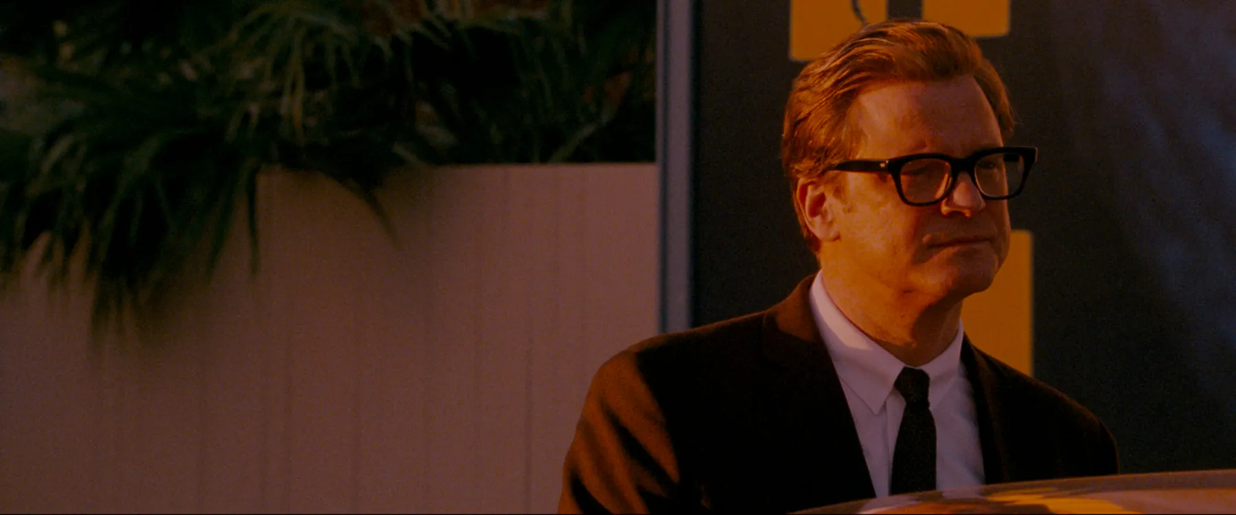 A man in glasses in shadow, warm light behind him