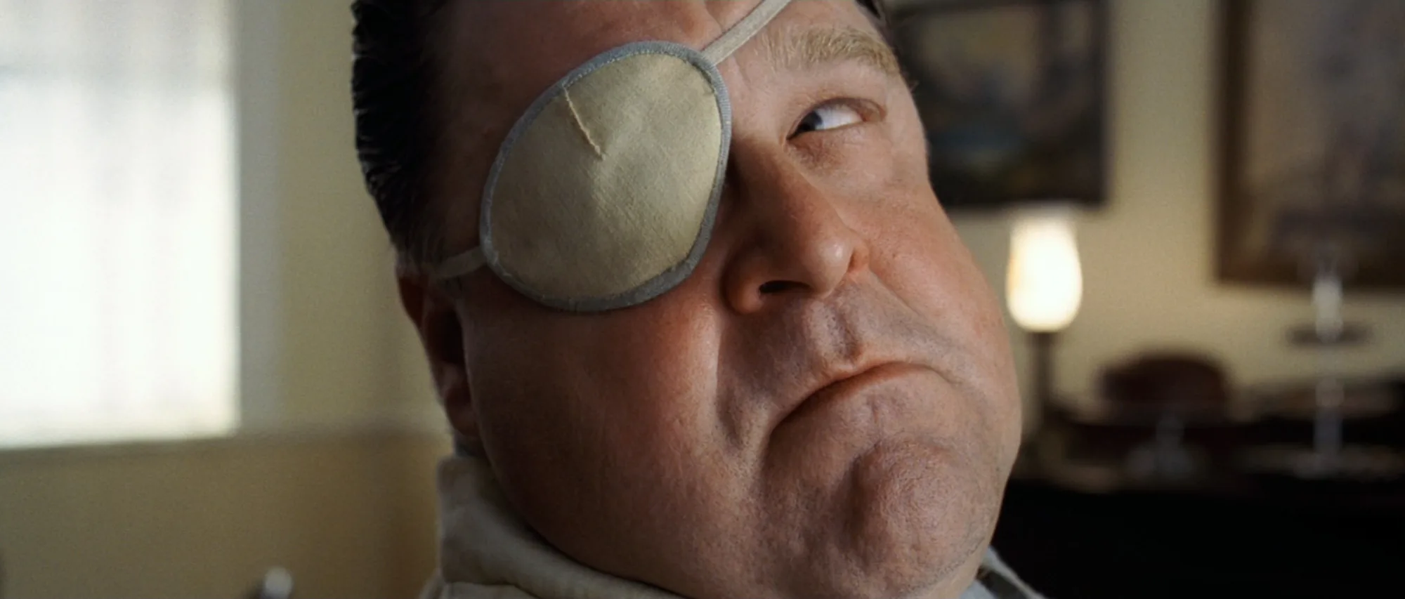 Close-up of a man with an eye patch, glancing sideways