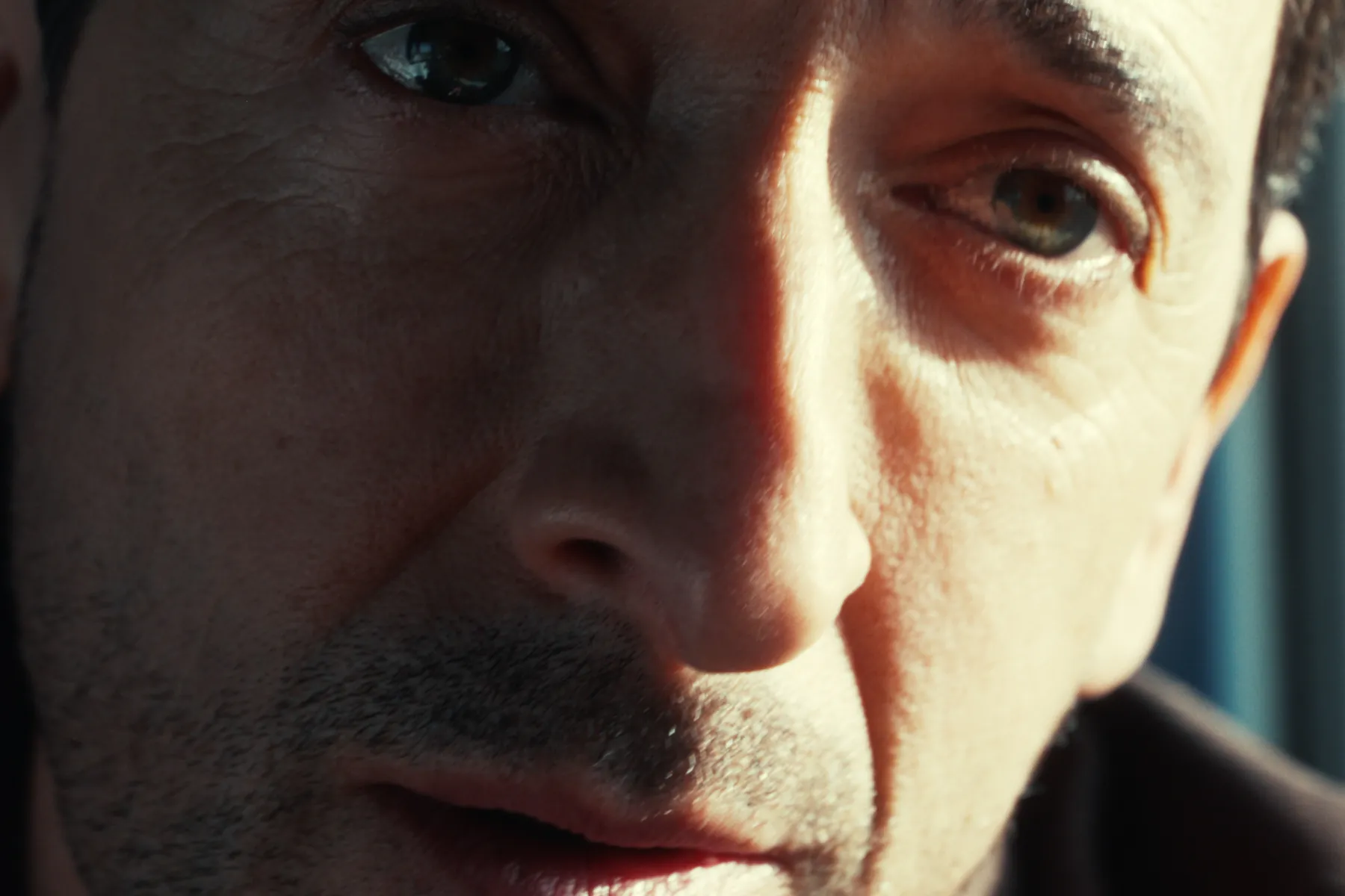 Extreme close-up of a man's face turned into hard warm light