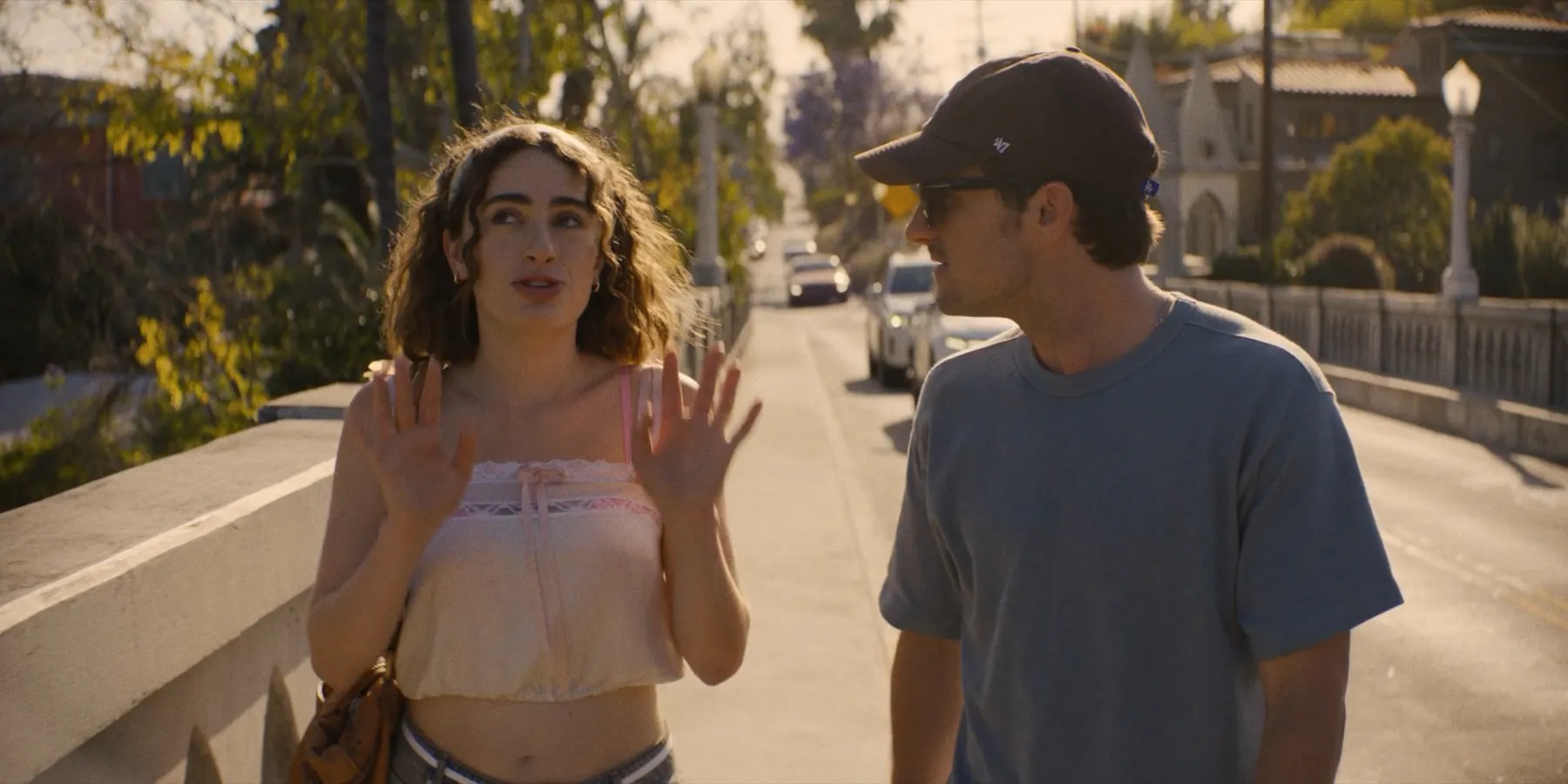 A young woman gesturing with both hands while a man in a cap listens