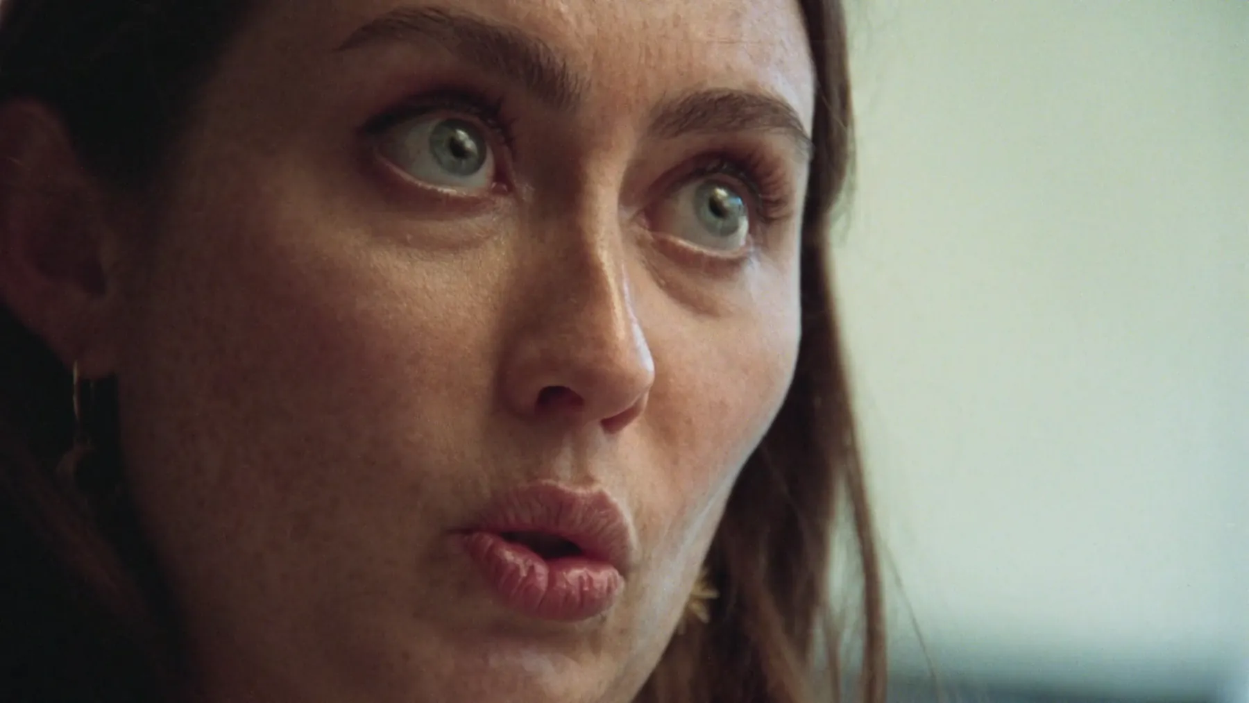 Close-up of a young woman mid-sentence, eyes wide