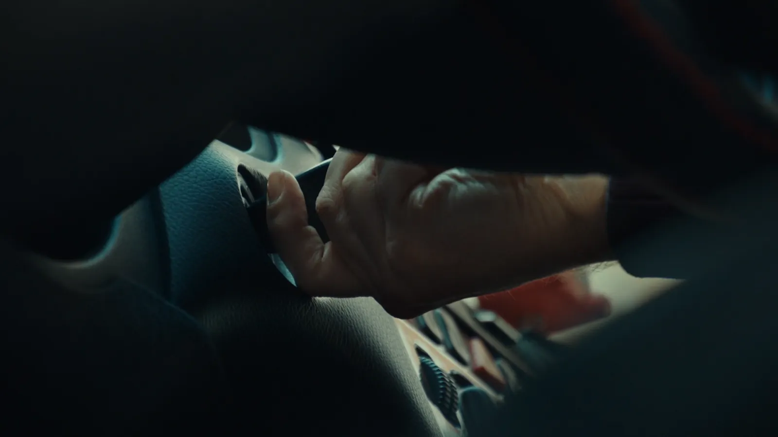 A finger pressing a hazard light button in a dark car interior