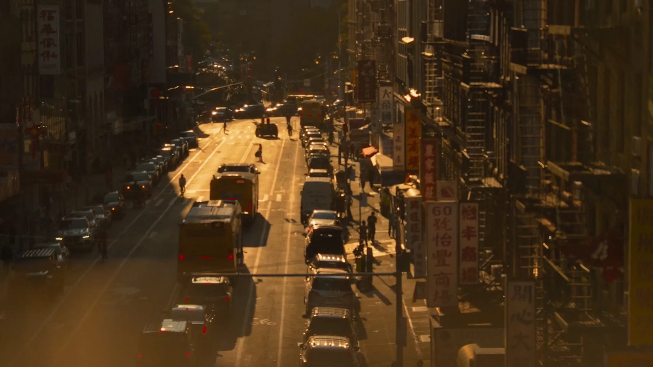 A city street in low golden light, traffic and signs