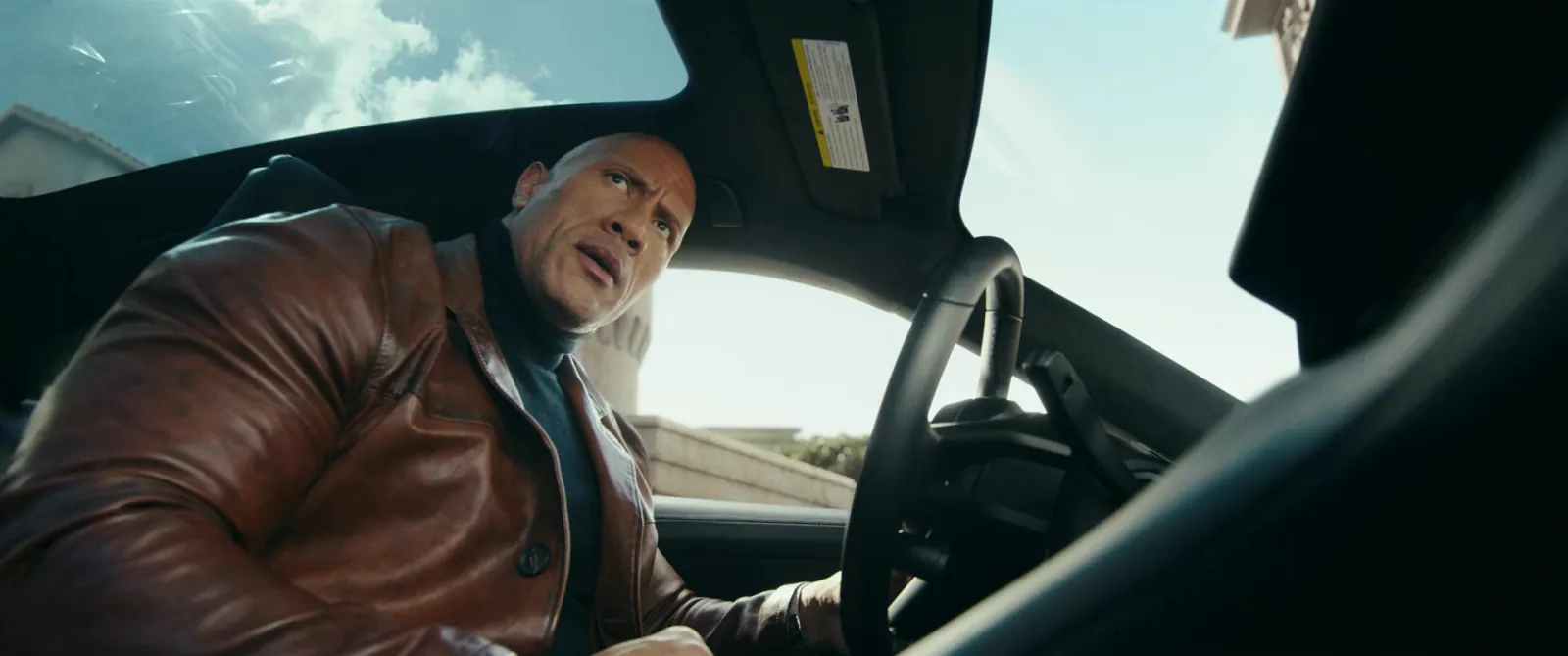 A man in the back seat of a car, knees raised