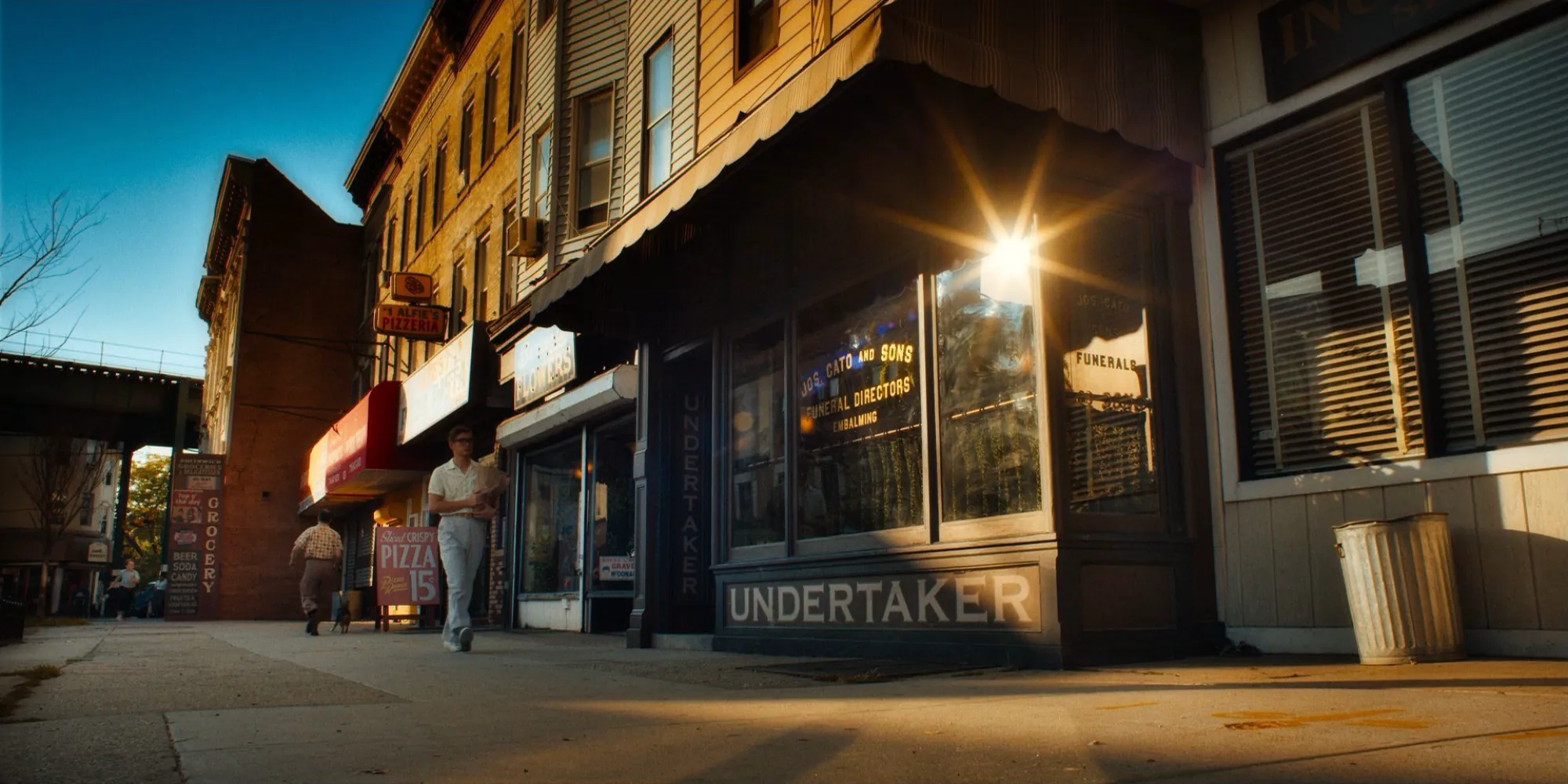 A storefront in low golden light, a man walking past